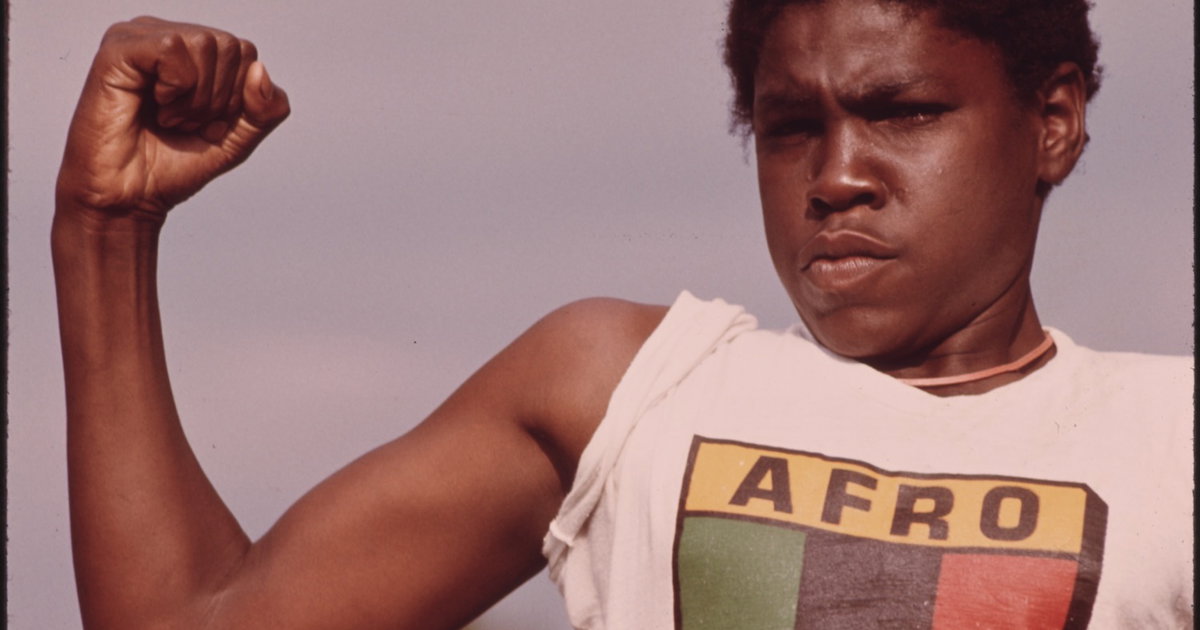 ‘“A young Black man showing his muscle during a small community program in Chicago...”’ by John H. White from Documerica (1973–4)